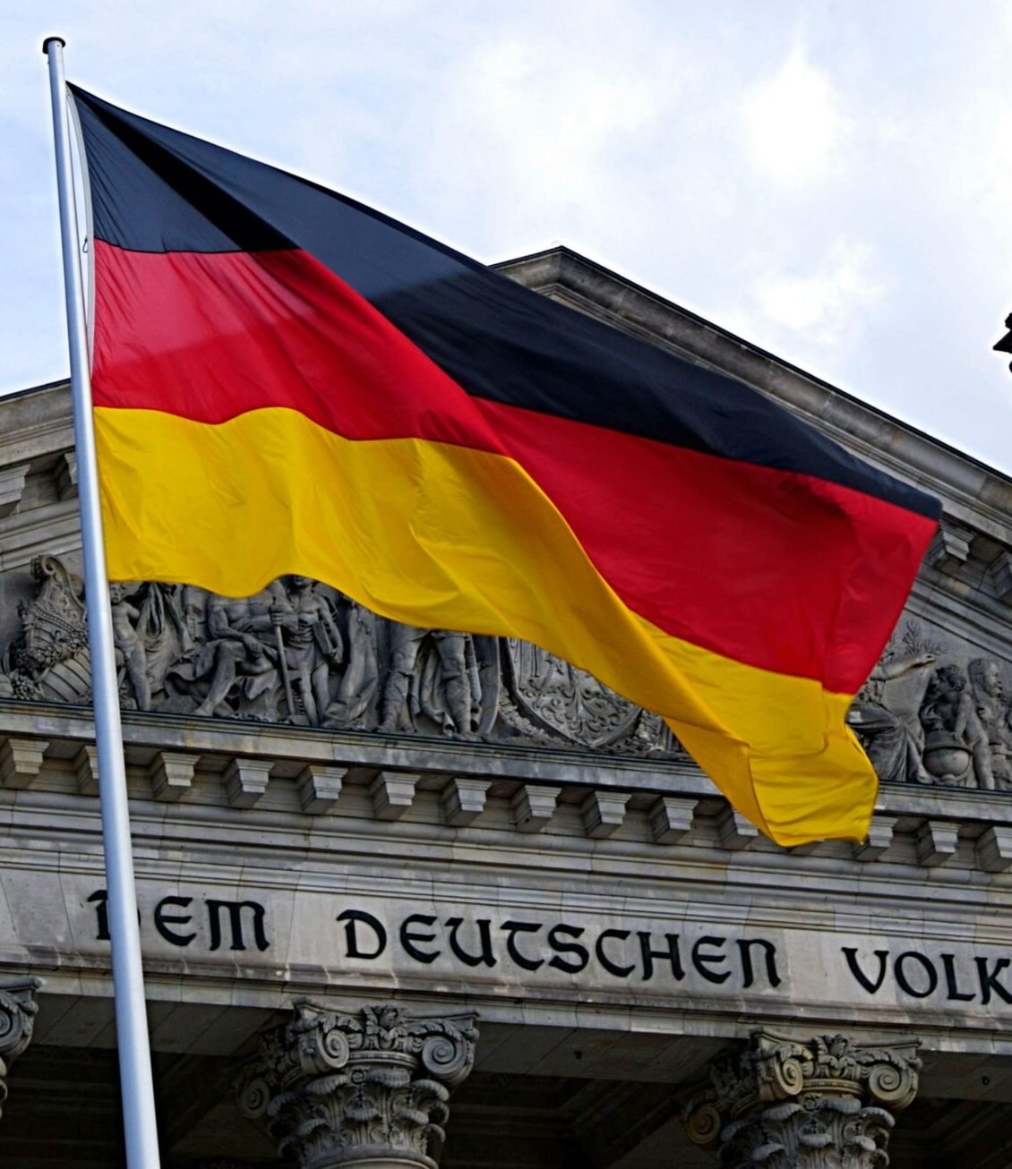 German national flag waving in front of the Reichstag building in Berlin, a symbol of democracy.